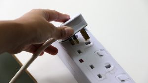 person putting plug in extension board