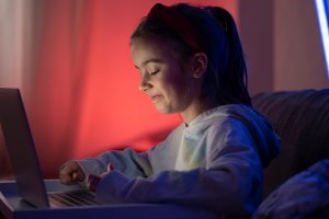 little girl play games on laptop late night